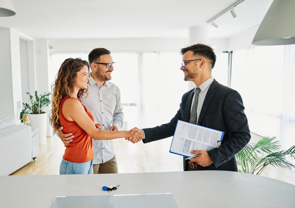 Real estate agent with couple shaking hands closing a deal.