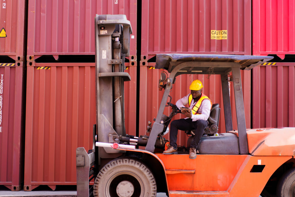 A man driving a forklift truck in a warehouse.