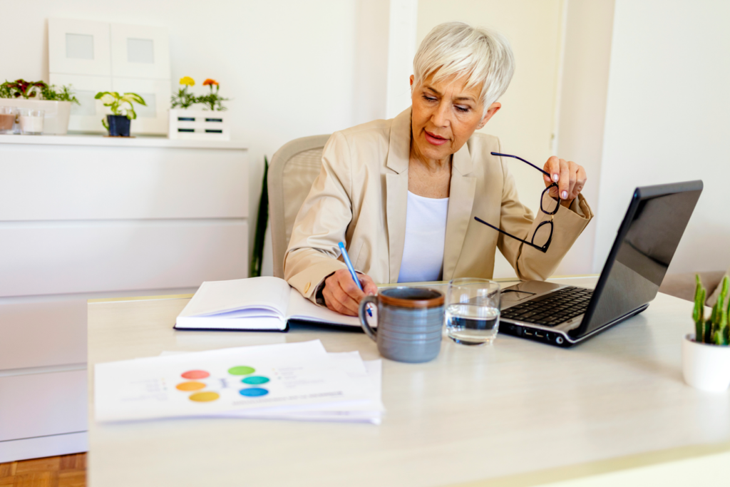 An older woman sitting at a desk with a laptop.