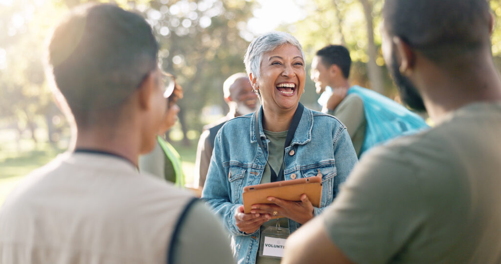 A woman in a park, holding a tablet with a group of people