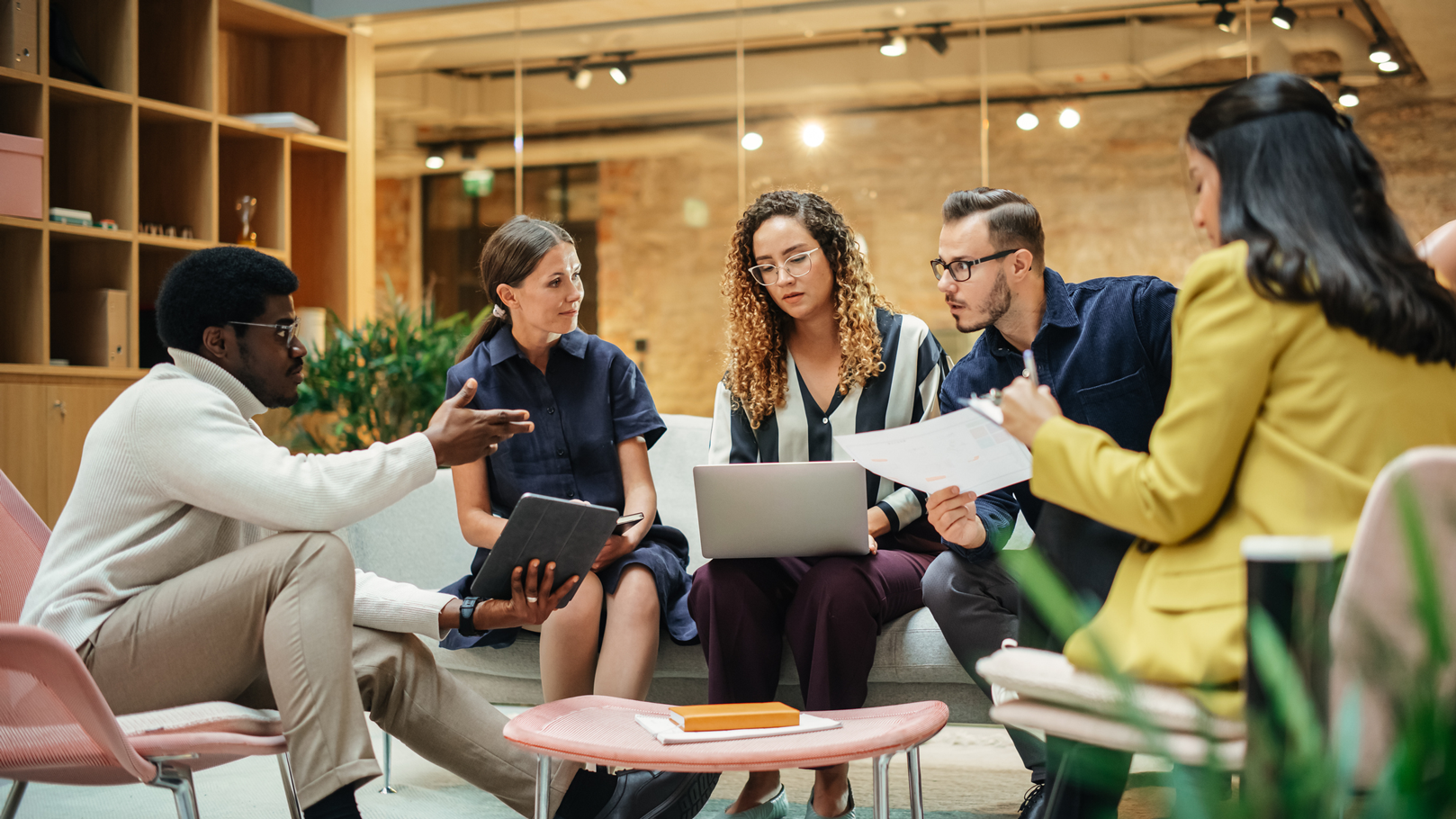 A diverse group of professionals sitting around a table with laptops, engaged in a business meeting