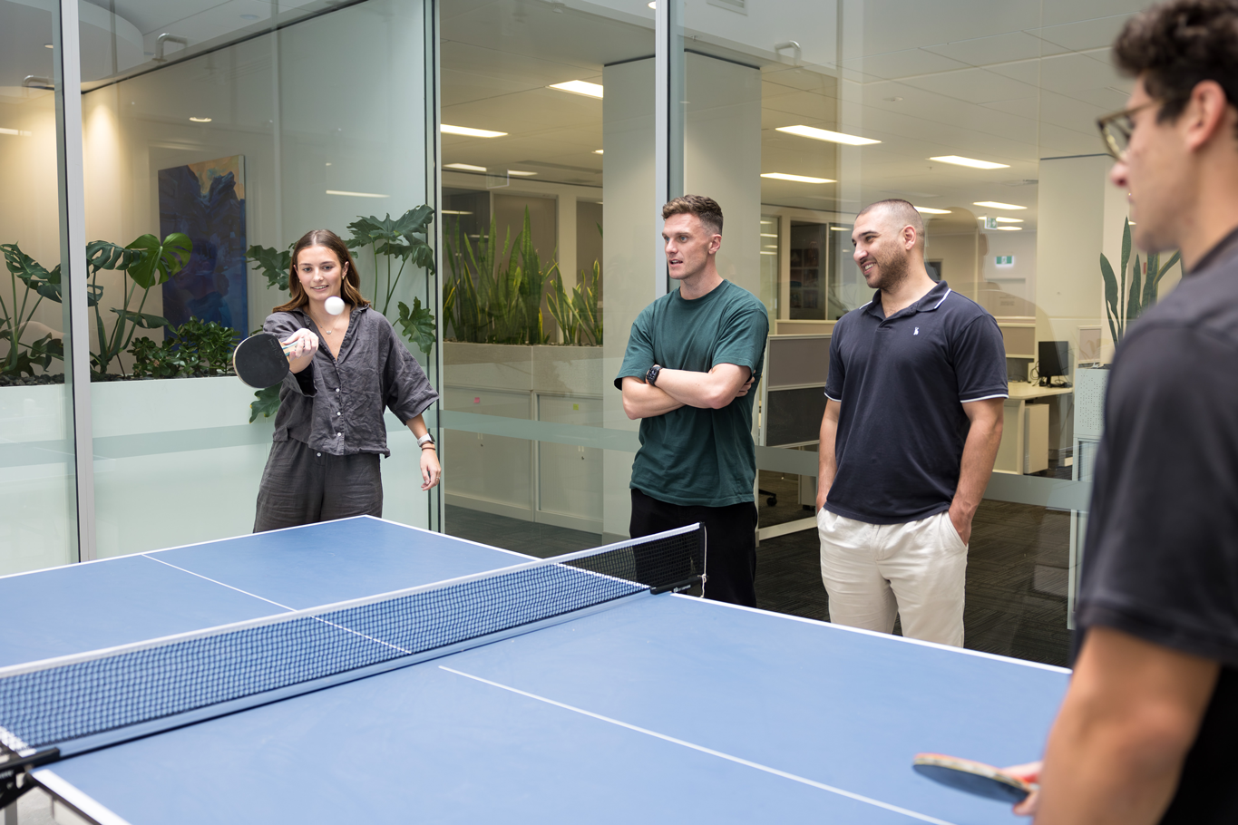 Diverse group of employees playing table tennis in the office